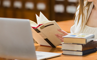 Photo of Student in Front of Laptop with Book